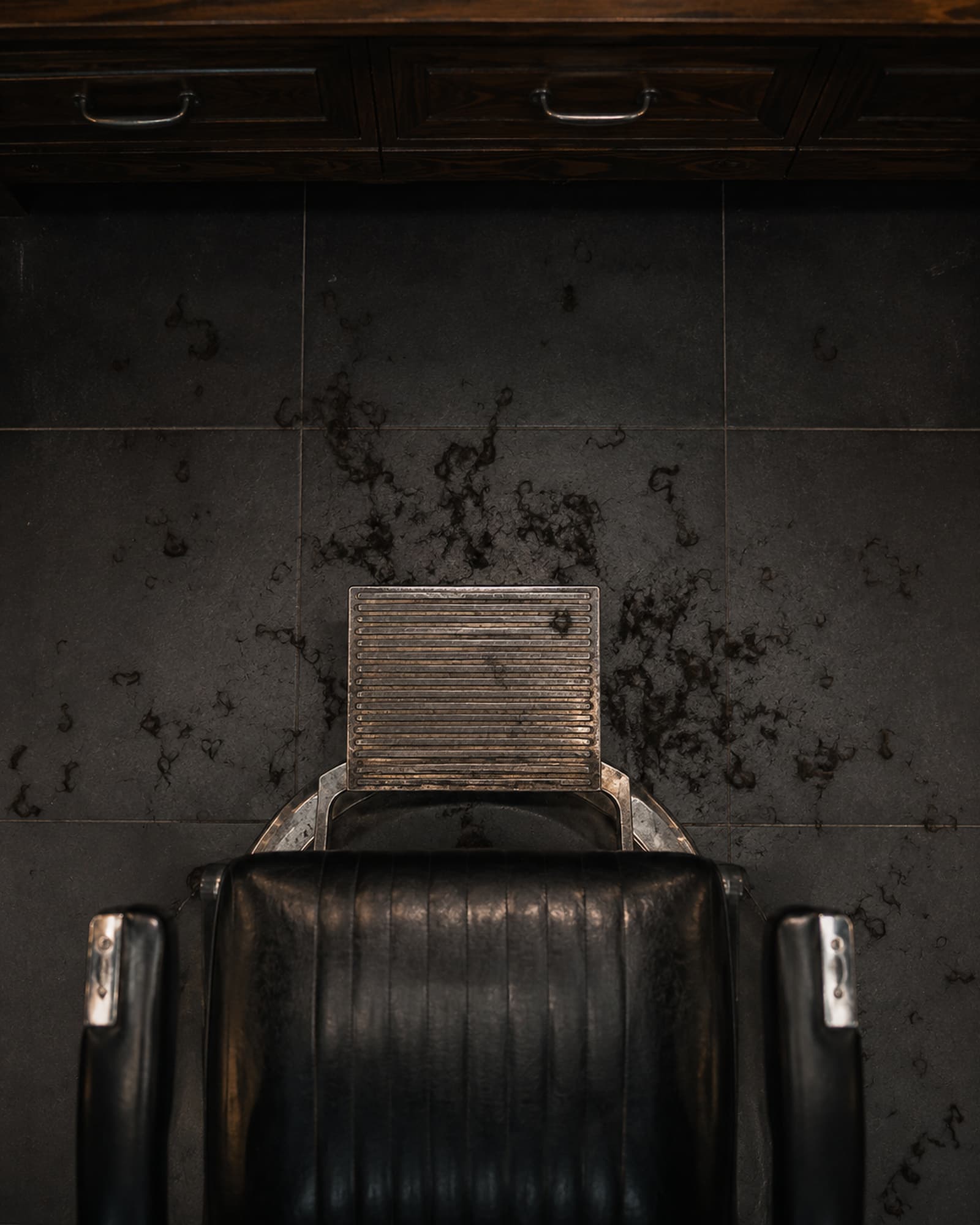 Cut hair on the floor beneath a chair at the end of the day